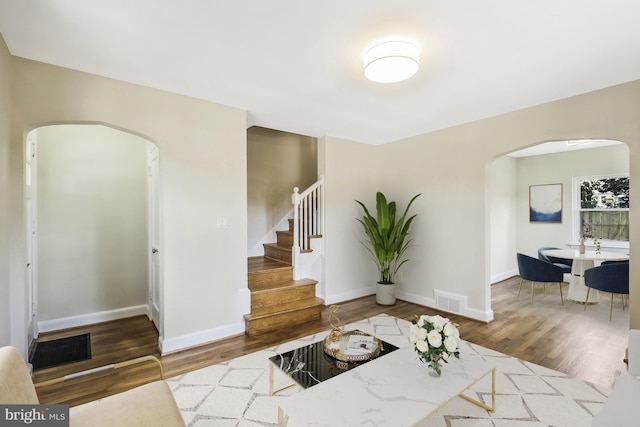 interior space with stairs, wood finished floors, arched walkways, and visible vents