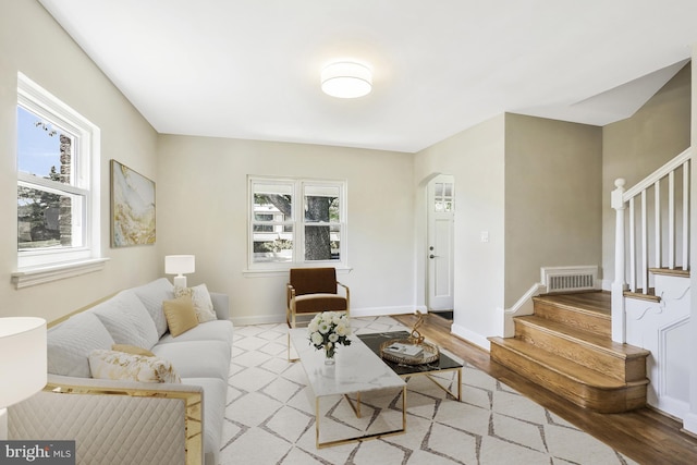 living area featuring stairs, baseboards, visible vents, and arched walkways