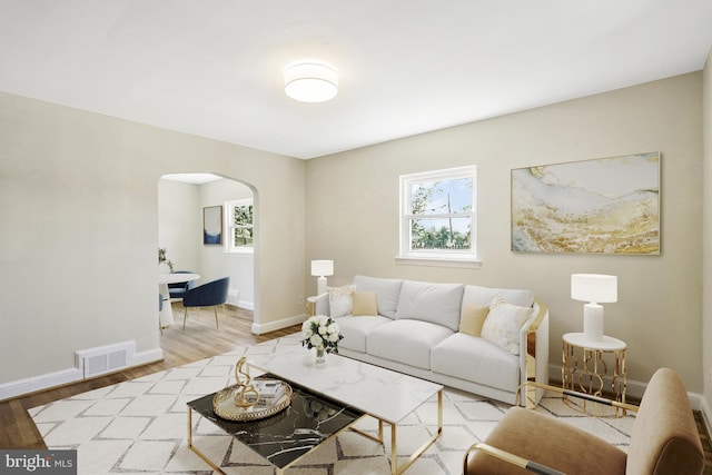 living area featuring arched walkways, visible vents, baseboards, and wood finished floors