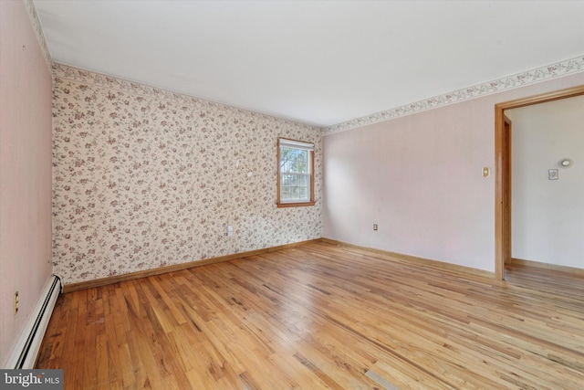 spare room with baseboard heating, wallpapered walls, baseboards, and wood-type flooring