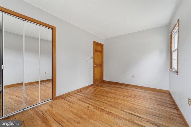 unfurnished bedroom featuring a closet, baseboards, and light wood-style floors