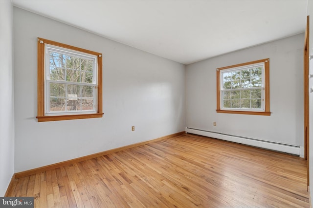 unfurnished room with a wealth of natural light, baseboards, baseboard heating, and hardwood / wood-style floors