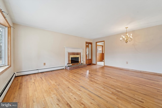 unfurnished living room featuring a notable chandelier, light wood-style flooring, a fireplace, and a baseboard heating unit