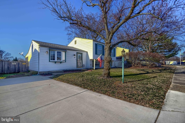 tri-level home with a front yard and fence