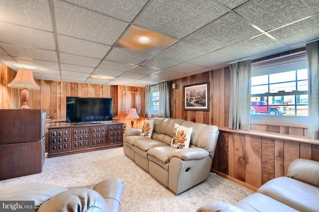 living area featuring carpet flooring, wood walls, plenty of natural light, and a paneled ceiling