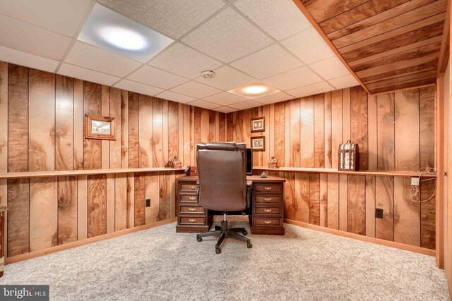 carpeted office with a drop ceiling and wood walls