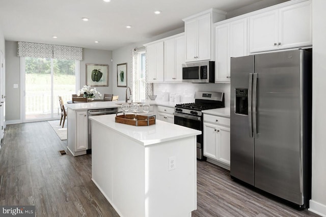 kitchen featuring a center island, appliances with stainless steel finishes, a peninsula, white cabinetry, and a sink