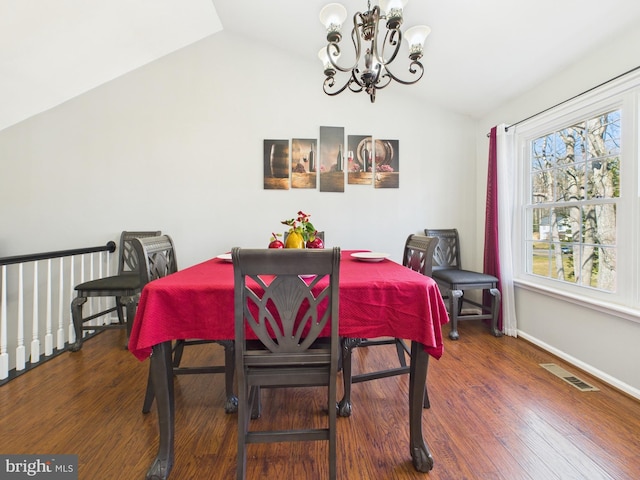 dining room with visible vents, baseboards, lofted ceiling, wood finished floors, and a notable chandelier