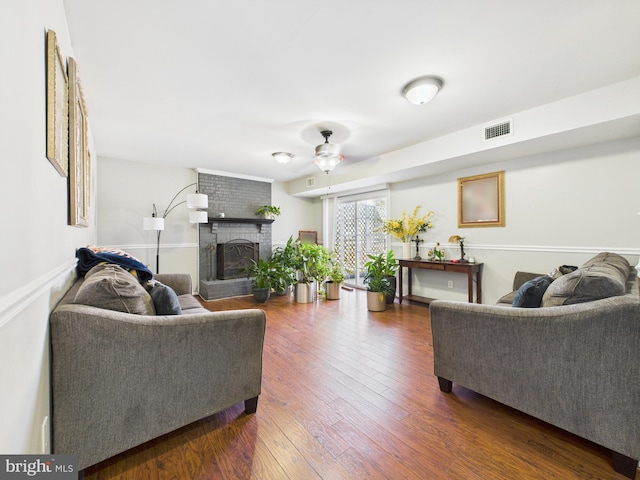 living room featuring visible vents, a brick fireplace, a ceiling fan, and hardwood / wood-style flooring