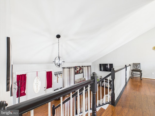 corridor featuring lofted ceiling, a notable chandelier, an upstairs landing, and wood-type flooring