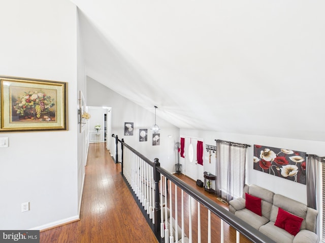 hallway featuring hardwood / wood-style flooring, an upstairs landing, and lofted ceiling