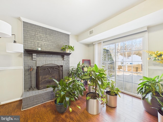 living area featuring visible vents, a fireplace, baseboards, and wood finished floors