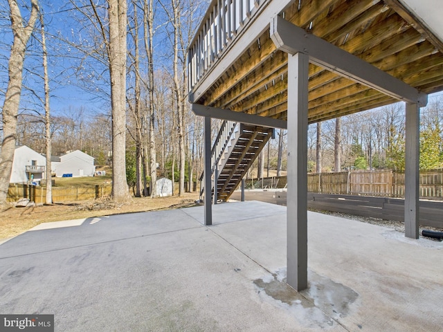 view of patio featuring a shed, an outbuilding, stairs, and fence