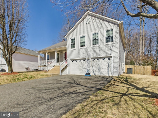 tri-level home featuring central air condition unit, aphalt driveway, a porch, fence, and an attached garage