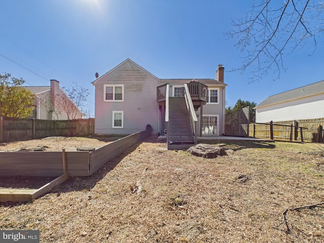 back of house featuring a chimney, stairs, and a fenced backyard