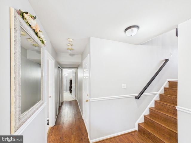 corridor with stairway, wood-type flooring, and baseboards