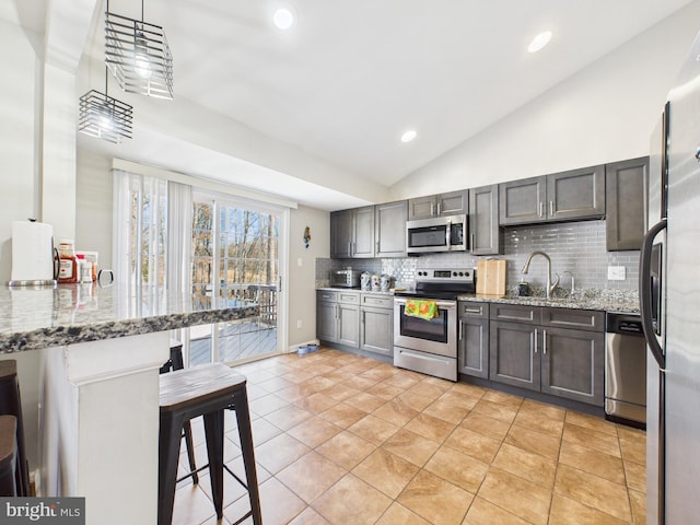 kitchen featuring a breakfast bar, light stone counters, tasteful backsplash, stainless steel appliances, and vaulted ceiling