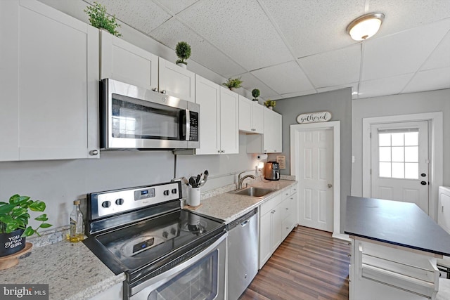 kitchen featuring white cabinetry, a drop ceiling, appliances with stainless steel finishes, and a sink