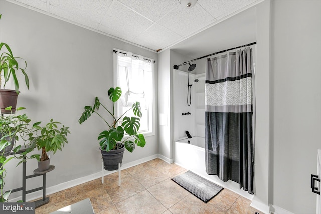 bathroom with a drop ceiling, shower / bath combo with shower curtain, and baseboards