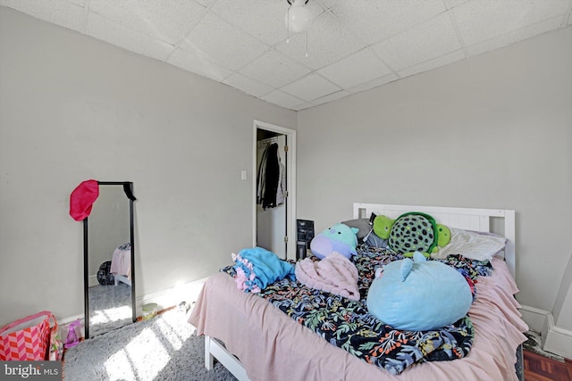 bedroom featuring a drop ceiling and baseboards