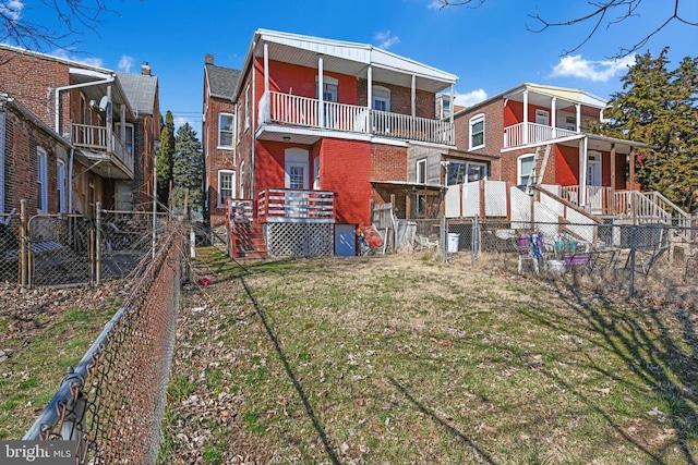 rear view of property with a balcony, a yard, fence private yard, and brick siding