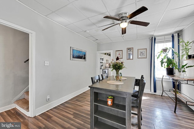 dining area with dark wood finished floors, stairway, baseboards, and a drop ceiling