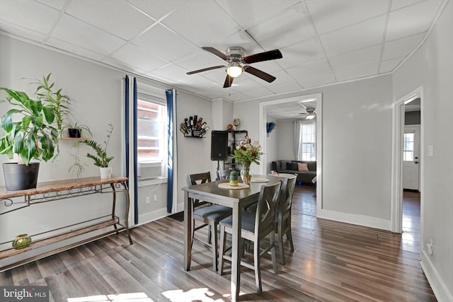 dining room with a drop ceiling, baseboards, and wood finished floors