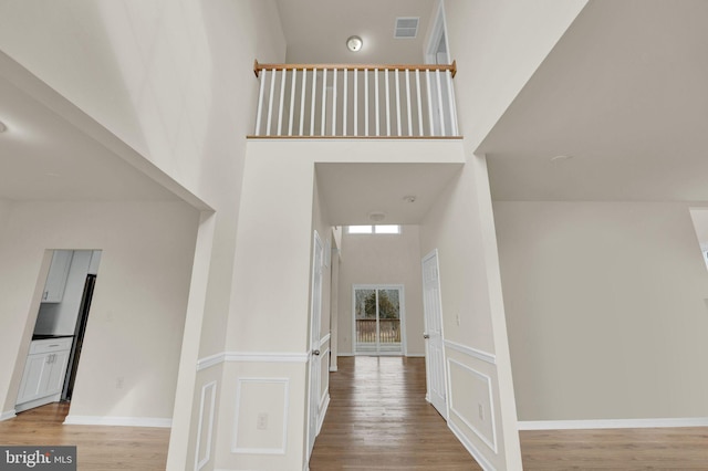 interior space featuring baseboards, visible vents, a high ceiling, and wood finished floors