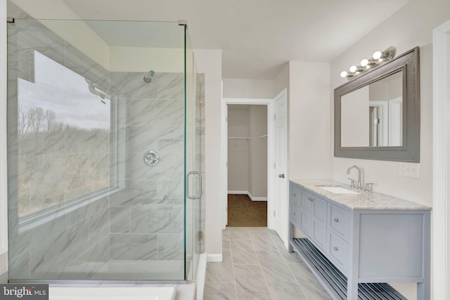 bathroom featuring a stall shower, baseboards, a walk in closet, and vanity