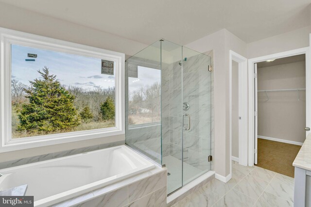 full bathroom featuring a spacious closet, a stall shower, baseboards, and a bath