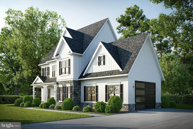 modern farmhouse style home with stone siding, a front lawn, board and batten siding, roof with shingles, and driveway