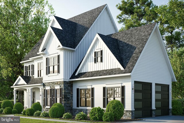 modern farmhouse with stone siding, board and batten siding, driveway, and a shingled roof