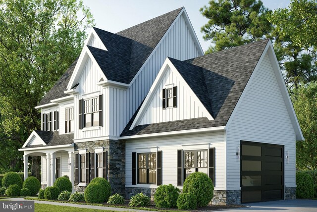 modern farmhouse style home with a garage, stone siding, board and batten siding, and roof with shingles