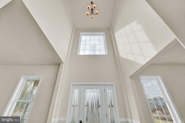 entrance foyer with a wealth of natural light, high vaulted ceiling, and an inviting chandelier