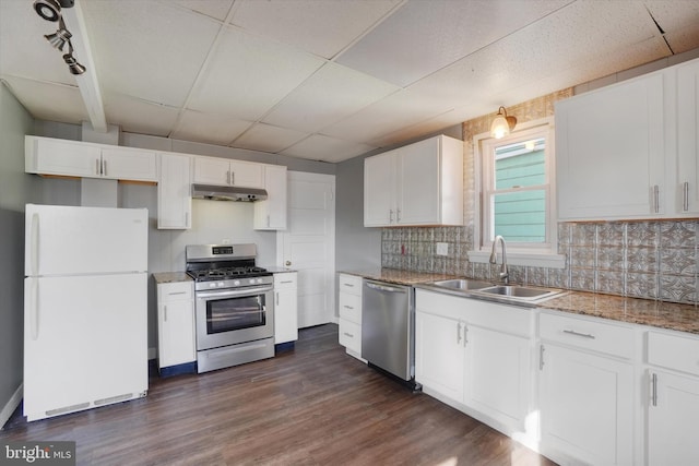 kitchen featuring dark wood-style flooring, a sink, white cabinets, under cabinet range hood, and appliances with stainless steel finishes