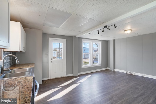 kitchen with baseboards, visible vents, a sink, dark wood-type flooring, and white cabinets