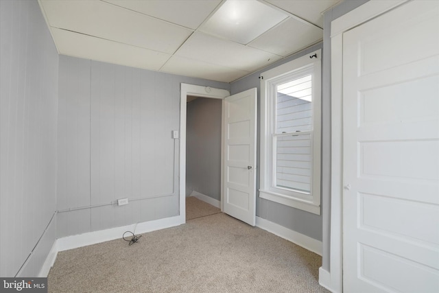 interior space with a drop ceiling, baseboards, and carpet