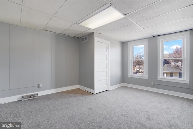 spare room featuring carpet flooring, a paneled ceiling, and visible vents