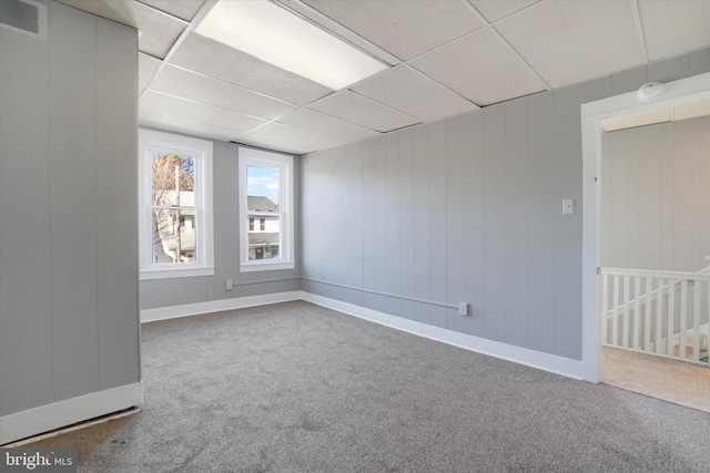 carpeted spare room with a drop ceiling, visible vents, and baseboards