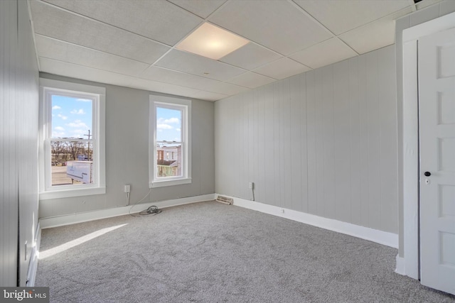 spare room featuring a paneled ceiling, carpet floors, and baseboards