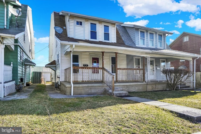 view of front of house featuring roof with shingles, a porch, and a front yard