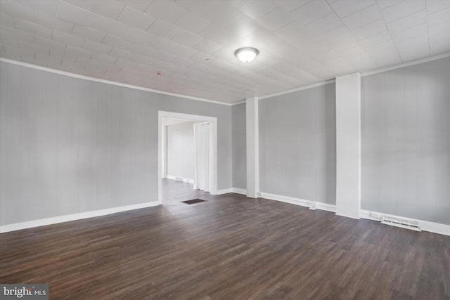 spare room featuring dark wood-style floors, visible vents, crown molding, and baseboards