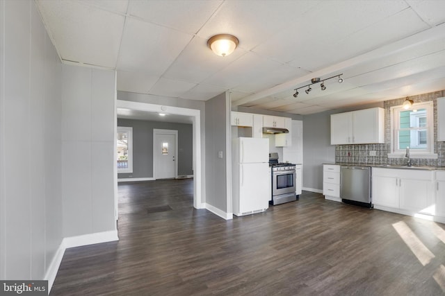 kitchen with dark wood finished floors, a sink, stainless steel appliances, under cabinet range hood, and white cabinetry