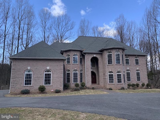 french country home with brick siding and roof with shingles