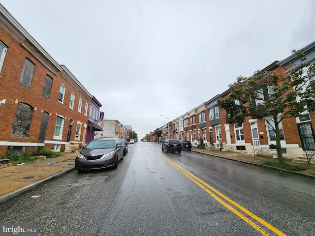 view of street with a residential view, curbs, street lights, and sidewalks