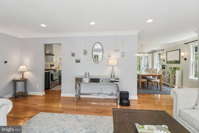 living room with a notable chandelier, recessed lighting, crown molding, and light wood-type flooring