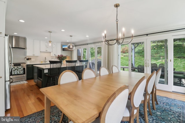 dining room with a notable chandelier, french doors, light wood-style floors, and recessed lighting