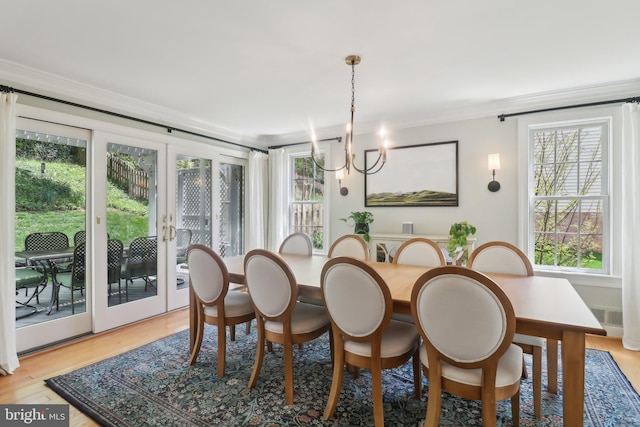 dining area with light wood finished floors, a healthy amount of sunlight, and crown molding