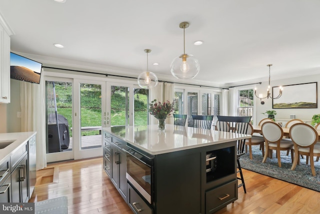 kitchen with built in microwave, light countertops, french doors, light wood-style flooring, and a kitchen bar