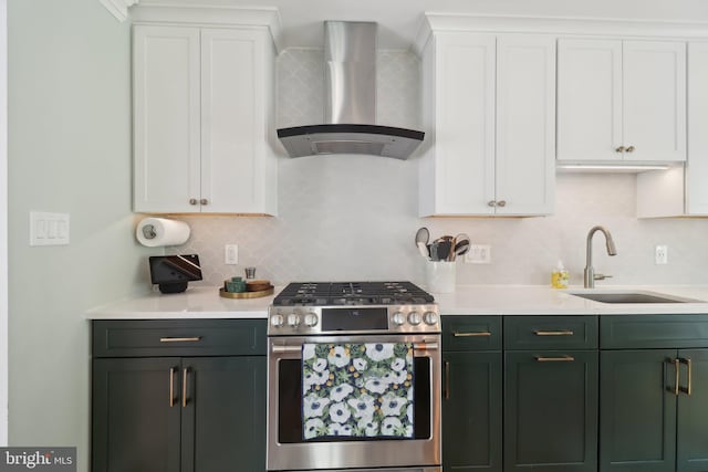 kitchen featuring wall chimney exhaust hood, light countertops, a sink, and stainless steel gas range